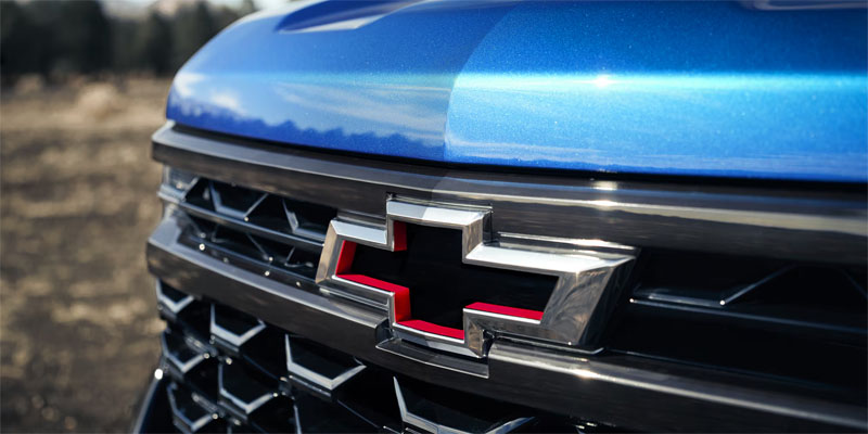 Close-up view of the Chevrolet bowtie emblem on the front grille of a blue vehicle.