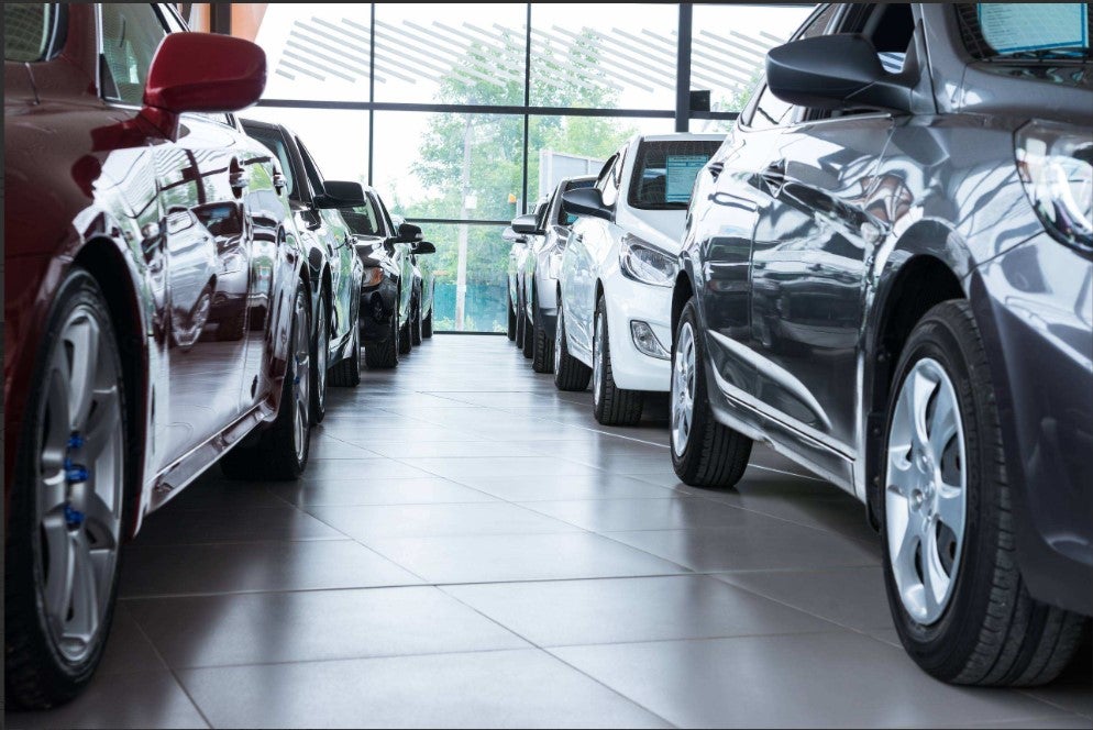 Rows of vehicles displayed inside a modern car dealership showroom.